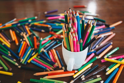 Close-up of multi colored pencils in cup on table