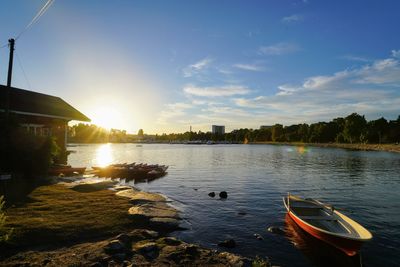 Boats in lake against sky during sunset