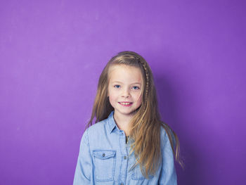 Portrait of smiling girl against purple background