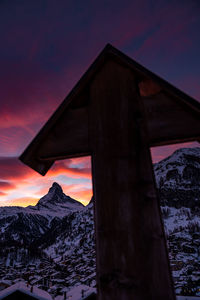 Built structure on snowcapped mountain against sky during sunset