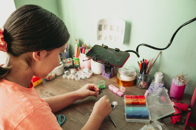 Girl making jewelry and vlogging with smart phone at home