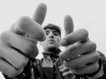 Low angle portrait of man gesturing against sky