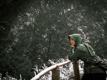 Side view of man standing by trees in forest