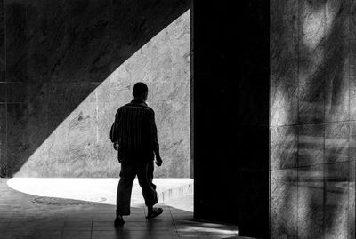 Rear view of man walking against wall