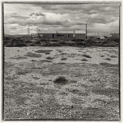 View of field against cloudy sky