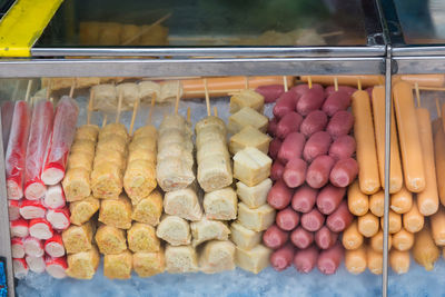 Raw sausages and meat arranged in display cabinet for sale at market