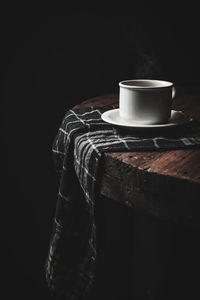 Close-up of coffee cup on table against black background