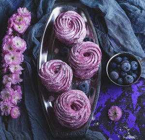 High angle view of sweet food with blueberries and flowers on table