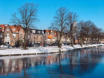 Canal by buildings against sky during winter