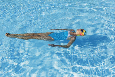 Woman relaxing in clear blue swimming pool