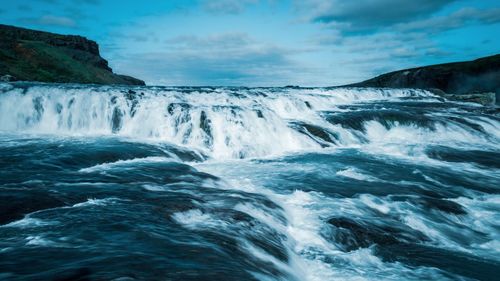 Scenic view of waterfall against sky