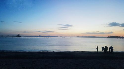 Silhouette people on beach against sky during sunset