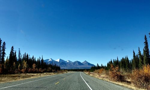 Empty road against clear blue sky