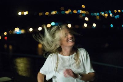 Full length of smiling girl against illuminated sky at night