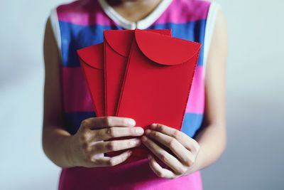 Midsection of girl holding red envelopes