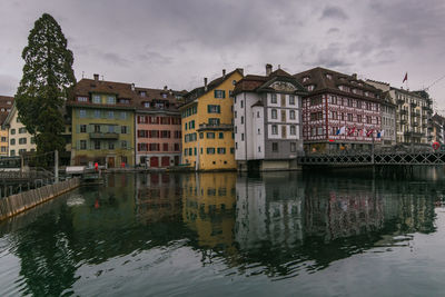 Reflection of buildings on river against sky in lucerne