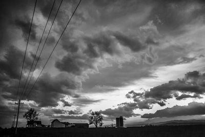 Low angle view of power lines against cloudy sky