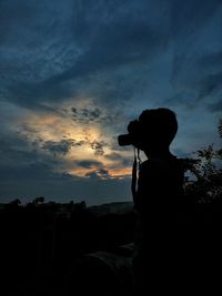 Silhouette man photographing against sky during sunset