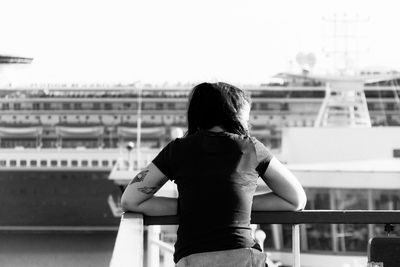 Rear view of woman leaning on railing