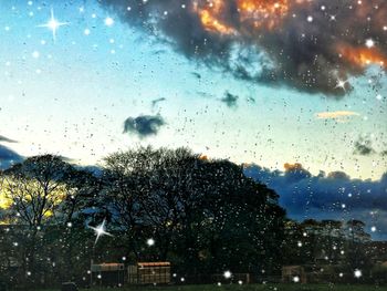 Raindrops on glass window against sky during rainy season