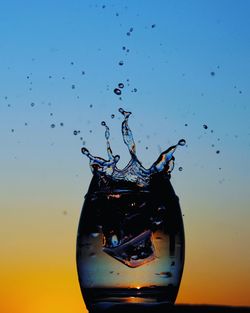 Close-up of water splashing on glass against sky