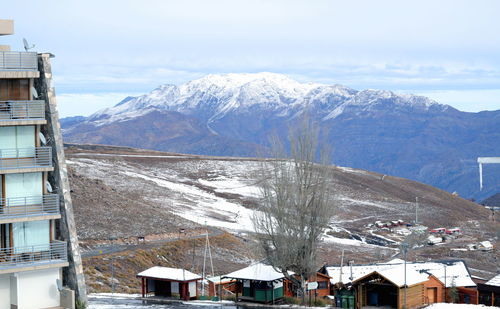 Snow covered houses and mountains against sky