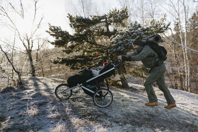 Man pushing pram uphill at winter