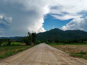 Road leading towards mountains against sky