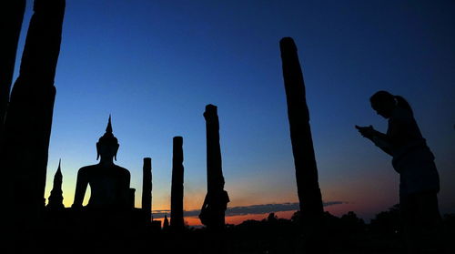 Silhouette statue against blue sky during sunset