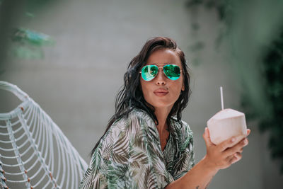 Portrait of woman holding sunglasses