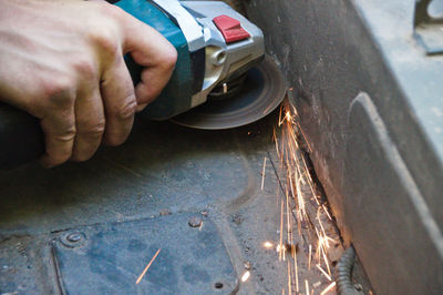Close-up of hand cutting metal with angle grinder