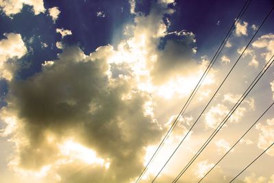 Low angle view of power lines against cloudy sky