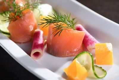 Buffet serving of pickled salmon slices with radish, cucumber and orange cubes