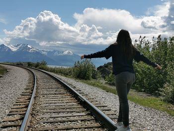 Rear view of woman standing on railroad track