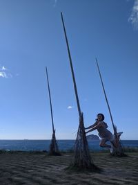Young woman on beach against blue sky