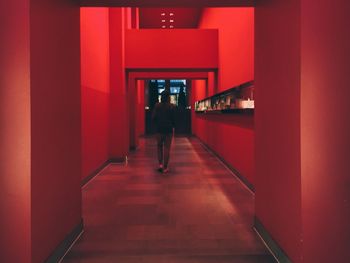 Full length rear view of person walking in passageway of illuminated building