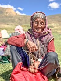 Portrait of senior woman sitting on grassy field