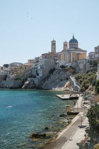 Buildings by sea against clear sky