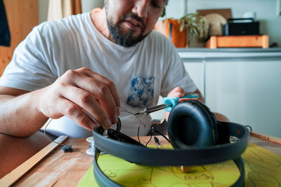 Repairing electronic circuit board inside headphones with soldering iron at home. diy project.