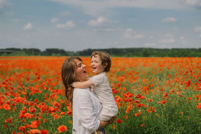 Happy mother's day. little boy and mother is playing in a beautiful field of red poppies