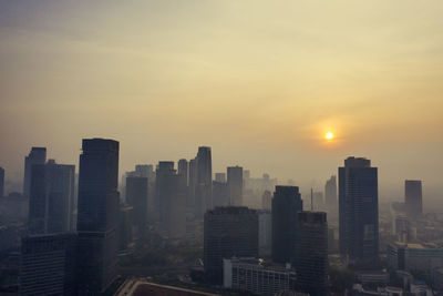 Modern buildings in city against sky during sunset