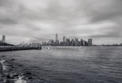 City at waterfront against cloudy sky