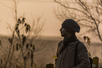 Young man looking at view against sky during sunset