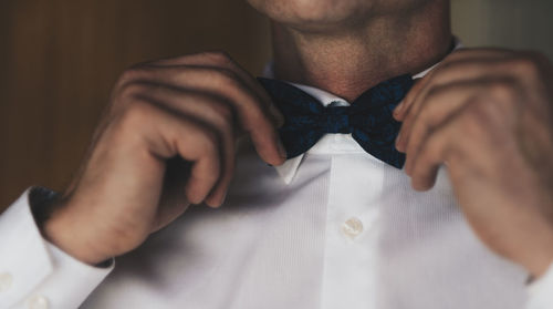 Midsection of man touching bow tie