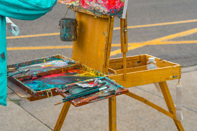 Paintbrushes and pallete on easel at footpath