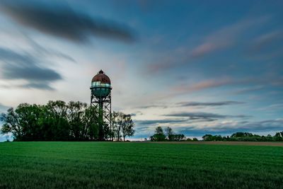 Traditional windmill on field against sky during sunset