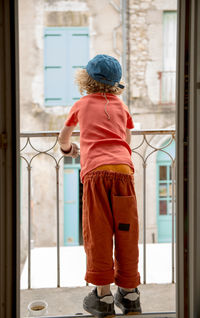 Rear view full length of boy standing in balcony