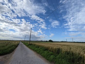 Road amidst field against sky