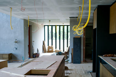 Selective focus on electrical wire hanging from ceiling with perspective of house under construction