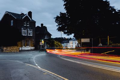 Light trails on road by buildings in city at night